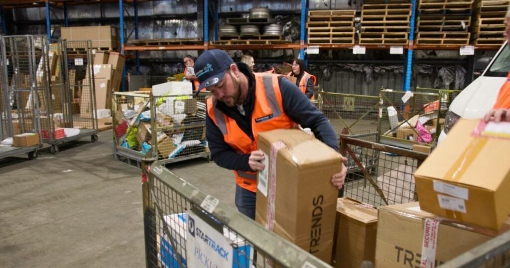 warehouse staff efficiently unloading boxes in a well-organized warehouse, showcasing the effectiveness of logistics software