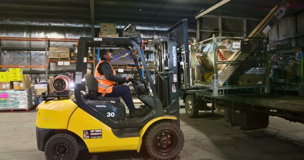 A worker operating a forklift, efficiently loading packages onto pallets as part of logistics operations in a warehouse