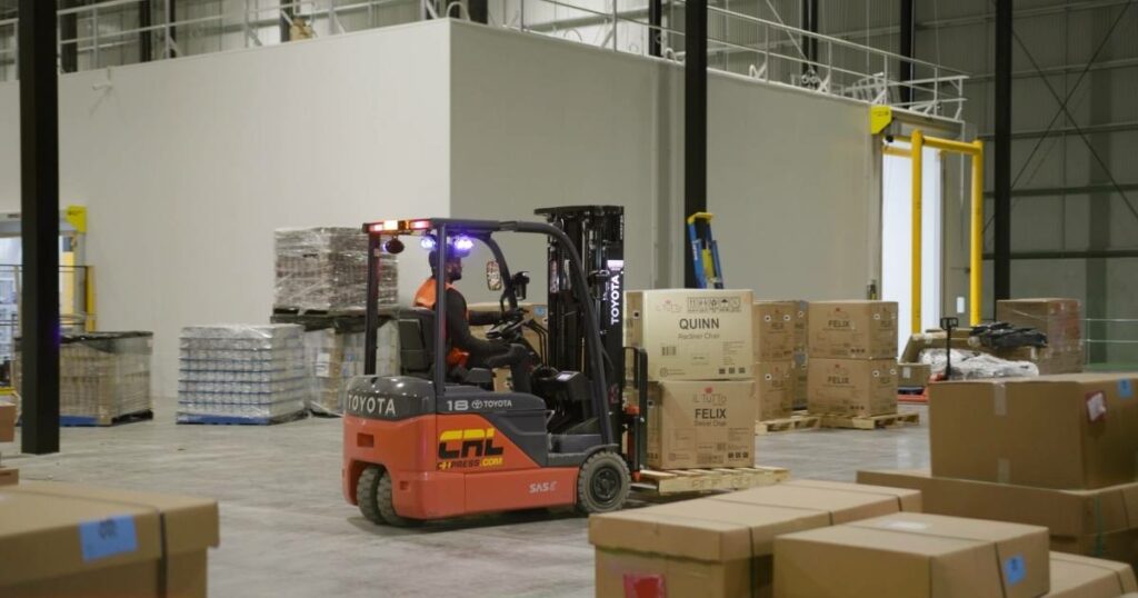 man operating a forklift, efficiently transferring packages in a logistics operation