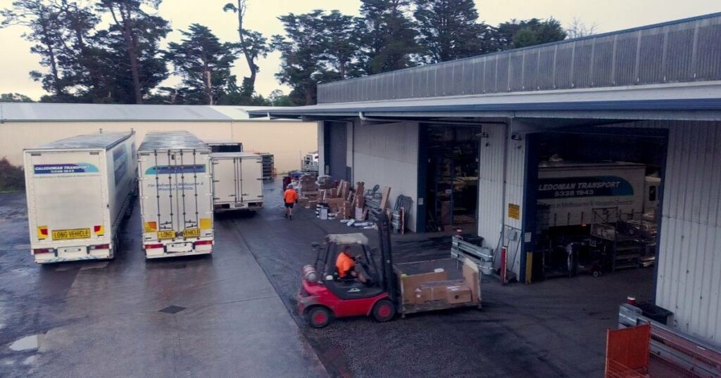 Busy warehouse scene with logistics operations in full swing: workers, forklifts, conveyor belts, and inventory movement showcasing efficient warehouse management