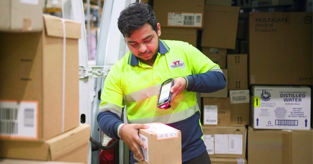 man diligently scanning packages, showcasing the integration of logistics software for efficient logistics management and tracking