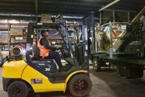 A worker operating a forklift, efficiently loading packages onto pallets as part of logistics operations in a warehouse