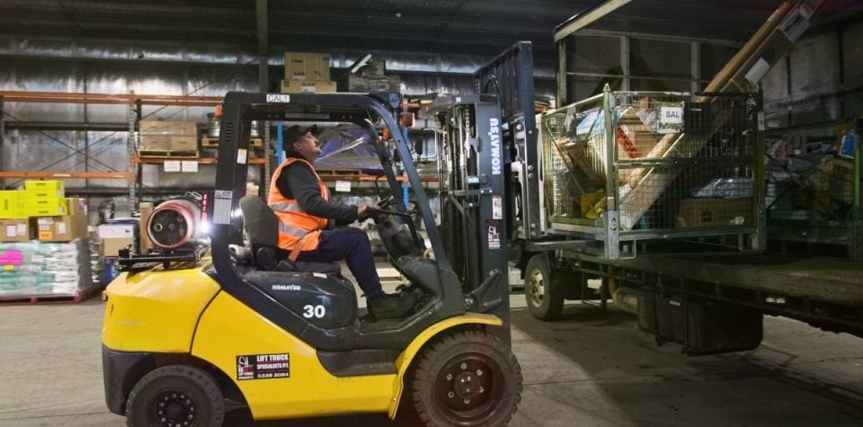 A worker operating a forklift, efficiently loading packages onto pallets as part of logistics operations in a warehouse