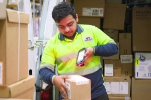 man diligently scanning packages, showcasing the integration of logistics software for efficient logistics management and tracking