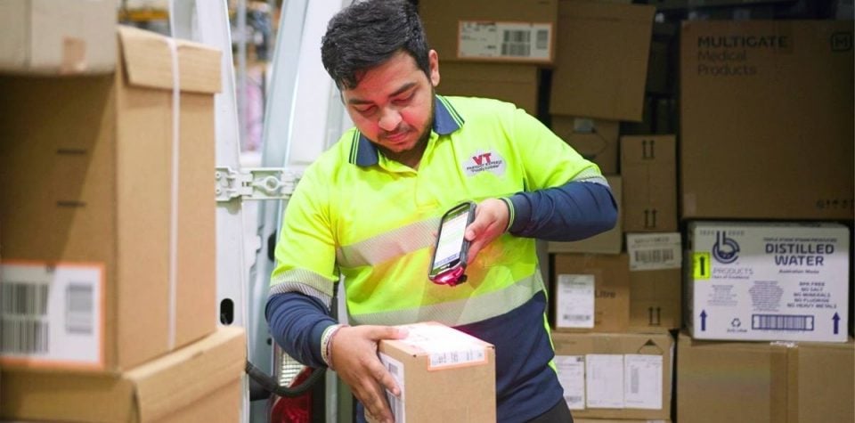 man diligently scanning packages, showcasing the integration of logistics software for efficient logistics management and tracking