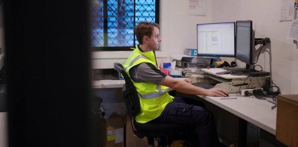 a man using desktop computer for logistics software, streamlining supply chain management